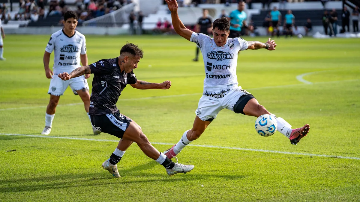 A soccer game in progress, with two players from opposing teams vying for control of the ball.